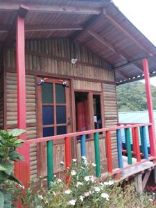 a small wooden cabin with a colorful railing at Las cabañas del escobo - CABAÑA TUCÁN in Nimaima