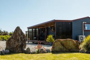a house with a large rock in front of it at Te Awa Cottages in Franz Josef