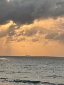 a cloudy sky over the ocean with a ship in the distance at Gracelands Beach Lodge in Ramsgate