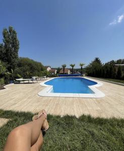 a person sitting on the grass next to a swimming pool at Residence Provence New in Vrdnik