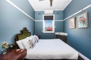 a blue bedroom with a bed and a window at The Paragon Hotel in Mudgee