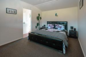 a bedroom with a large bed with a black headboard at Te Awa Cottages in Franz Josef