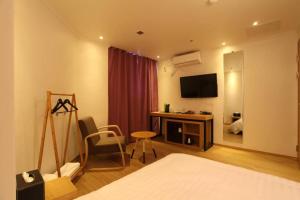 Habitación de hotel con cama y escritorio con TV. en Hotel Violet, en Goyang