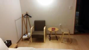 Zimmer mit einem Stuhl, einem Tisch und einem Bett in der Unterkunft Hotel Violet in Goyang