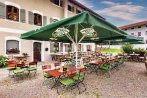 a group of tables and chairs under a large green umbrella at Hotel Wirt z´ Engelsberg in Engelsberg