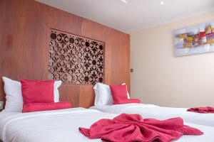 Dos camas en una habitación de hotel con almohadas rojas. en Lake Elementaita Mountain Lodge en Nakuru