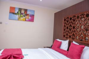 1 dormitorio con cama blanca y almohadas rojas en Lake Elementaita Mountain Lodge en Nakuru