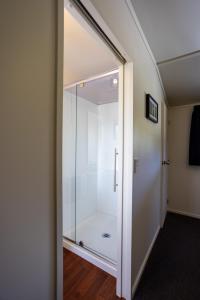 a glass shower door in a room with a hallway at Te Awa Cottages in Franz Josef