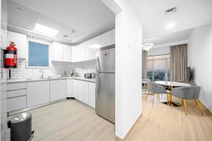 a white kitchen with a table and a refrigerator at ALH Vacay - Modern 2 Bedroom suitable for family in Dubai