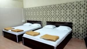 two beds in a room with a wall at Shree Yatri Niwas in Kolhapur
