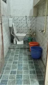 a bathroom with a toilet and a blue bucket at Shree Yatri Niwas in Kolhapur
