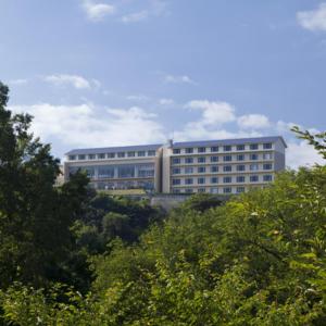 un grand bâtiment au milieu de quelques arbres dans l'établissement Kyukamura Setouchi-Toyo, à Saijo