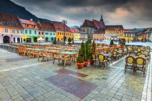 a group of tables and chairs on a city street at Rossmarkt Haus in Braşov