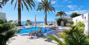 a resort with a swimming pool with palm trees and the ocean at Maresía Village in Los Realejos