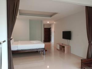 a bedroom with a bed and a flat screen tv at Baan Ampai Beach Hotel in Hua Thanon Beach
