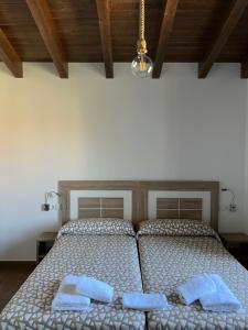 een slaapkamer met een bed met twee handdoeken erop bij PENSION ORUEIRO VILASERIO in Negreira