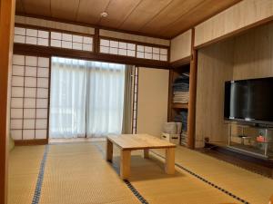a living room with a table and a tv at Guest house Nagi - Vacation STAY 21489v in Kanayama
