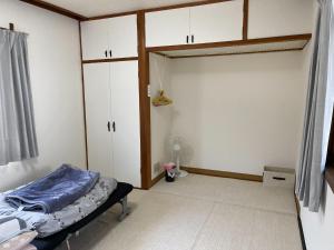 a bedroom with a bed and white cabinets and a door at Guest house Nagi - Vacation STAY 21489v in Kanayama