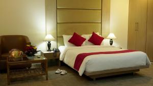 a bedroom with a bed with red pillows and a chair at Asia Pacific Hotel in Dhaka