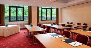 een eetkamer met tafels, stoelen en ramen bij Victor's Residenz-Hotel Berlin in Berlijn