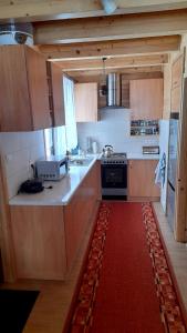 uma cozinha com armários de madeira e um tapete vermelho em Domek Pod Smrekiem em Marcinkowice