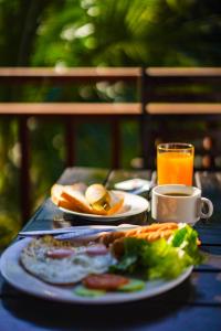 stół z talerzami jedzenia i filiżanką soku pomarańczowego w obiekcie Vang Vieng Savanh Sunset View Resort w mieście Vang Vieng