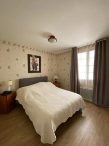 a bedroom with a white bed and a window at L’Apazys in Saint-Cast-le-Guildo