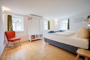 a bedroom with a bed and a chair and windows at Gutshof Schirgiswalde in Schirgiswalde