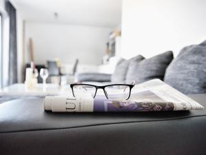 a pair of glasses sitting on a couch with a magazine at Mönkebude Coastal Garden Stay in Mönkebude +30 photos