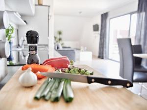 a knife on a cutting board with vegetables on a table at Mönkebude Coastal Garden Stay in Mönkebude
