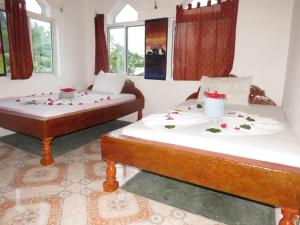 2 Betten in einem Zimmer mit Blumen darauf in der Unterkunft Mudi House in Jambiani