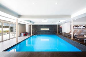 een groot zwembad met blauw water in een gebouw bij Relais & Châteaux Le Brittany & Spa in Roscoff