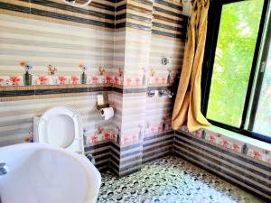 a bathroom with a tub and a toilet and a window at Jungle Heaven Hotel and Cottage in Bhurkīā