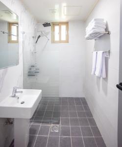 a white bathroom with a sink and a shower at Jeju Arumdaun Resort in Seogwipo