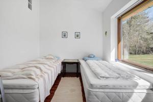 a row of beds in a room with a window at Lækkert kvalitetshus tæt på vandet in Nibe