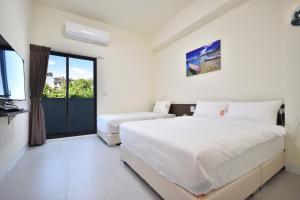 a bedroom with two beds and a balcony at v2民宿 in Taitung City