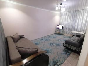 un salon avec un canapé et une chaise dans l'établissement Квартира на Бр Жубановых 283 корпус 1, à Aqtöbe
