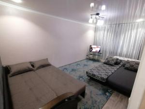 ein Schlafzimmer mit 2 Betten und einem TV in der Unterkunft Квартира на Бр Жубановых 283 корпус 1 in Aqtöbe