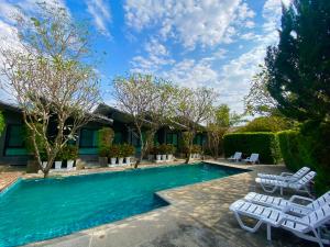 a swimming pool with white lounge chairs and trees at Family House Zen Boutique Resort in Pai