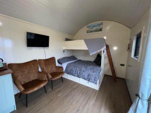 a small bedroom with a bed and two chairs at Slieve Gullion Getaways in Meigh