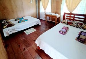 two beds in a room with wooden floors and windows at Batad Countryside in Banaue