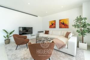 een woonkamer met een witte bank en een tv bij HigueronRentals Malibu in Málaga
