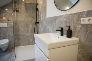 a bathroom with a sink and a shower and a mirror at Modernes Loft in Ramstein - mit Sauna & TLA in Ramstein-Miesenbach +4 photos