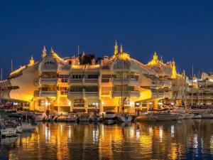 een groot gebouw met boten in een jachthaven 's nachts bij HigueronRentals Malibu in Málaga