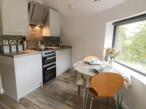 a kitchen with white cabinets and a table and a window at Moss Bank, Jacobs Wood in Keighley