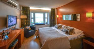 a bedroom with a large bed and a television at Hotel Aateli Lakeside in Vuokatti