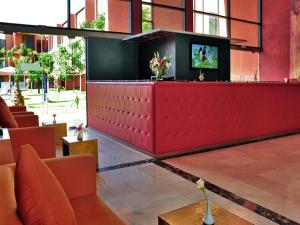 a lobby with a tv on a red counter at Rawabi Hotel Marrakech & Spa in Marrakech