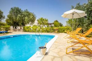 a swimming pool with a chair and an umbrella at Relais Trullo degli Emme in Ostuni