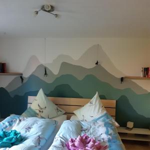 2 camas en un dormitorio con un mural de montaña en la pared en Ferienwohnung Glasperlenfloh, en Ilmenau