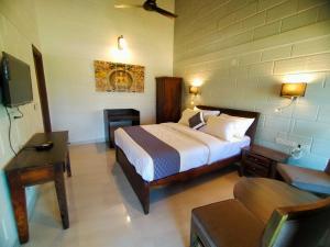 a bedroom with a bed and a couch and a tv at Coffeeberry Hills Chikamagalur in Chikmagalūr
